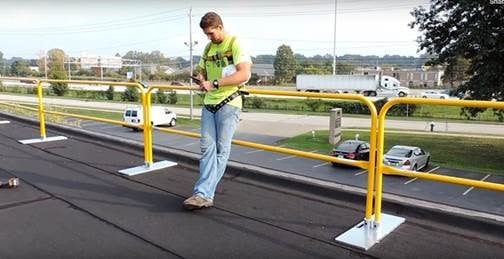 worker leaning against rooftop portable guardrail system